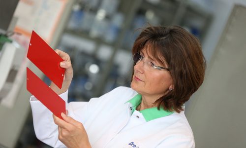 Mitarbeiterin bei der Farbkontrolle eines roten Lacks – Dreisol Coatings sorgt für präzise Farbgenauigkeit und Qualität in der Lackproduktion